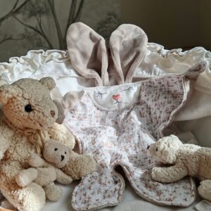 Doudou plat lapin Aube en gaze de coton fleurie et velours sable présenté dans un berceau - Cœur de Pinpin
