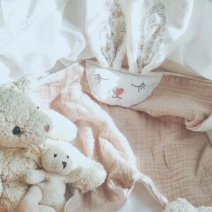 Doudou plat lapin Latté en gaze de coton beige nude présenté dans un couffin avec des peluches oursons - Cœur de Pinpin